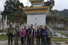 En af Rockjumpers fugleturgrupper i Bhutan tager et gruppebillede med et religiøst monument i baggrunden