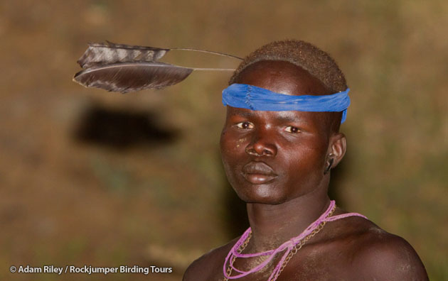 En nötkreatursskötare från Mursi har en vimpelvingad Nightjar-huvudbonad